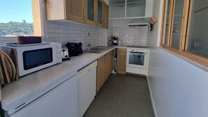 A compact kitchen with a microwave, toaster, sink, and oven. - Charming air-conditioned T2 near sea, 4 pers (Collioure)