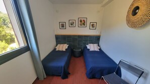 A small room with two beds, a chair, and a window. - Charming air-conditioned T2 near sea, 4 pers (Collioure)