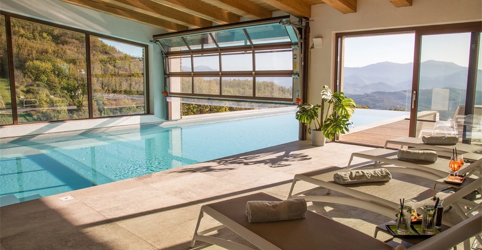 A modern indoor pool area with clear views of a mountainous landscape through large windows.