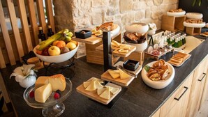 Un bufé con diversos quesos, frutas y repostería.