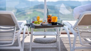 Una mesa con bebidas y aperitivos en un balcón con vistas a la montaña.