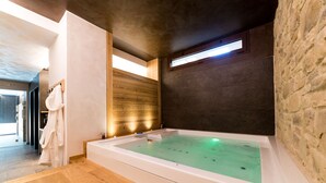 Un moderno spa con una bañera grande, paneles de madera y una pared de piedra.