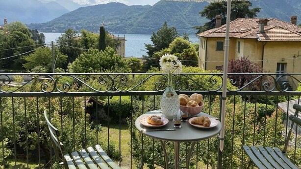 Ein Balkon mit einem Frühstückstisch, mit Blick auf einen See und Berge.