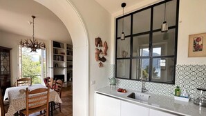 Eine Küche mit weißen Schränken, einem großen Fenster und einem Essbereich mit Tisch und Stühlen.