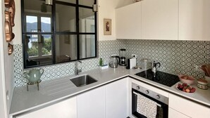Eine moderne Küche mit einem großen Fenster, Edelstahlgeräten und einer Wandfliese mit Muster.