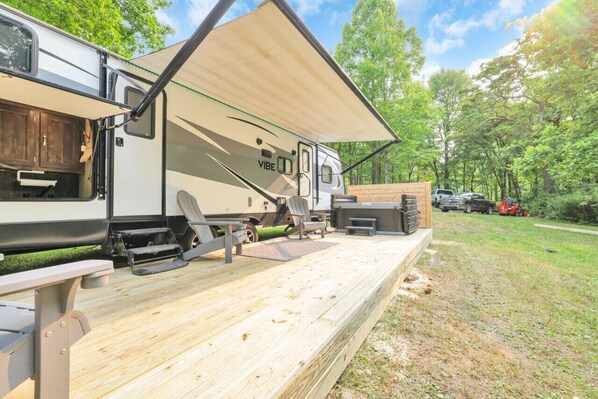 A recreational vehicle with a covered deck area, a picnic table, and a grill. - Chestnut Camper: Unique lodging experience! (Lancaster)
