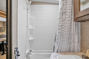 A bathroom with a bathtub, a shower, and a sink. - Chestnut Camper: Unique lodging experience! (Lancaster)