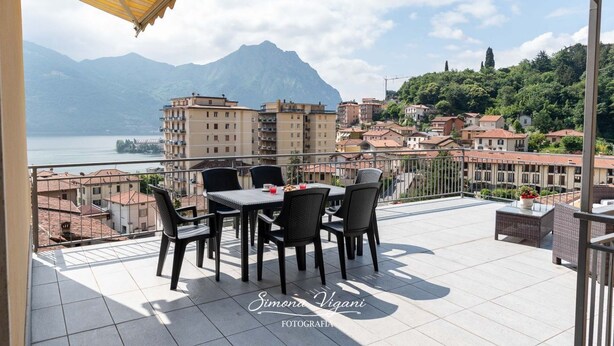 A terrace with a table and chairs, overlooking a lake and mountains. - bright and spacious apartment with large terrace overlooking the lake (Lovere)