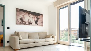 A living room with a beige sofa, a large window, and a flat-screen TV. - bright and spacious apartment with large terrace overlooking the lake (Lovere)
