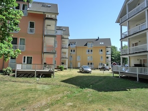 A multi-story residential building with balconies, a grassy courtyard, and parked cars. - 3-zi-fewo für 4 Pers. mit Wlan, Strandnah (Graal-Müritz)