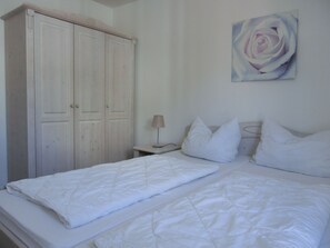 A bedroom with two beds, a wardrobe, a nightstand, a lamp, and a painting of a rose. - 3-zi-fewo für 4 Pers. mit Wlan, Strandnah (Graal-Müritz)