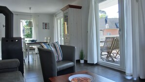 Ein modernes Wohnzimmer mit einer Couch, einem Essbereich und Blick ins Freie.