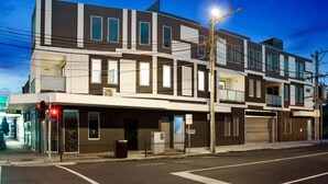 Un immeuble moderne à plusieurs étages, doté d’une façade plane, de grandes fenêtres et d’une entrée bien visible au rez-de-chaussée.