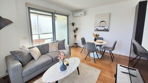 Un salon moderne avec un canapé gris, une table basse blanche et un coin repas comprenant une petite table et des chaises.