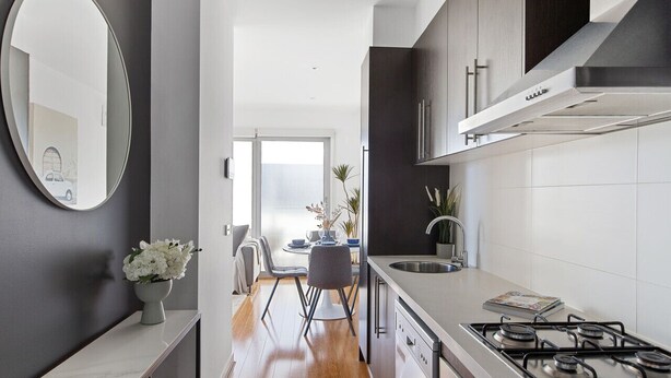 Une cuisine moderne avec une cuisinière à gaz, des meubles de couleur sombre et un grand miroir.