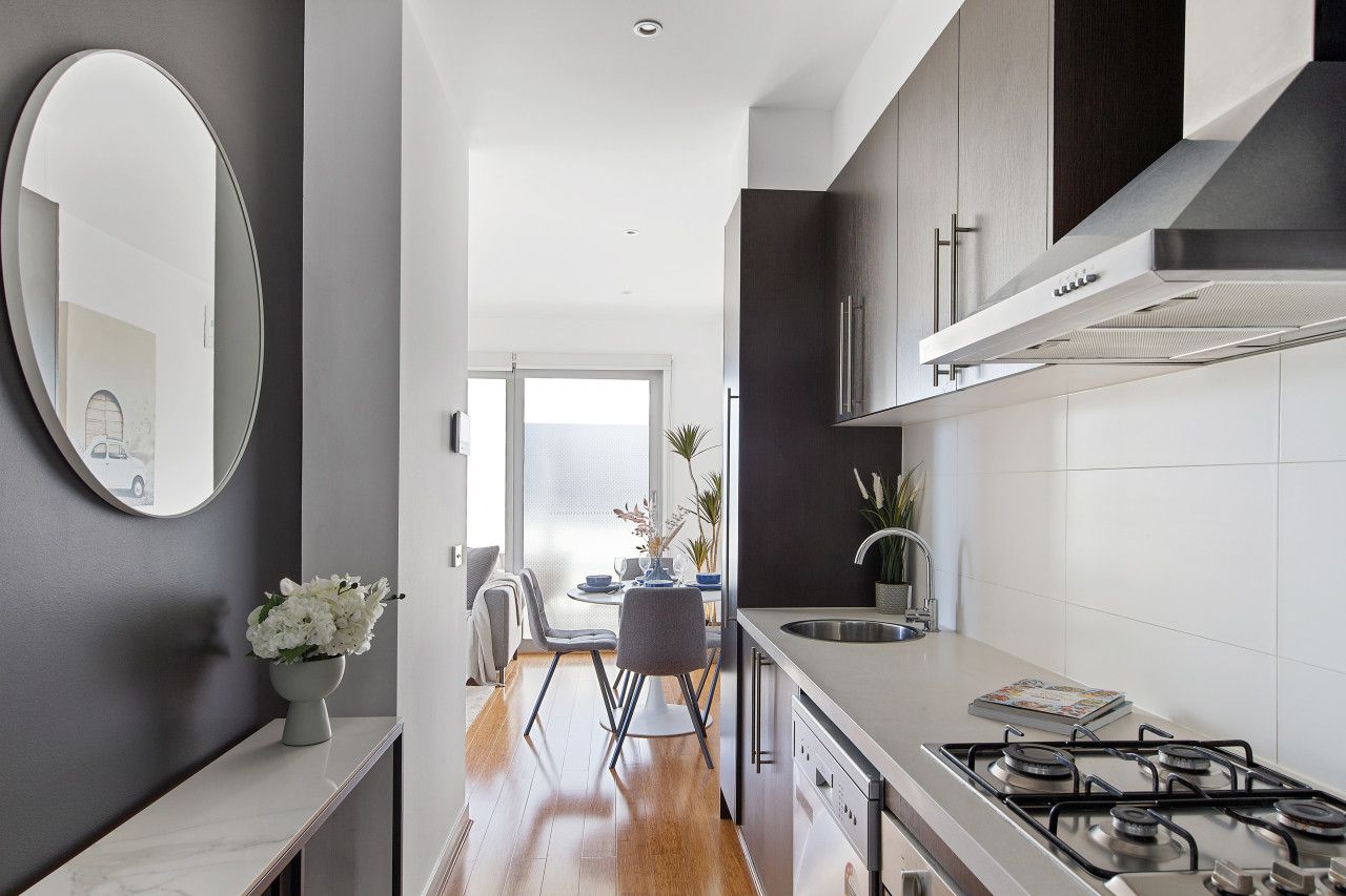 A modern kitchen with a gas stove, dark cabinets, and a dining area with a table and chairs.