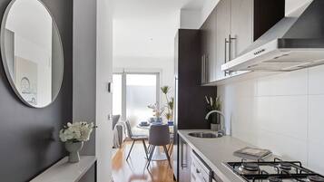 A modern kitchen with a gas stove, dark cabinets, and a dining area with a table and chairs.