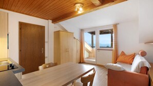 A room with a wooden dining table, a sofa, and a staircase leading to an upper level.
