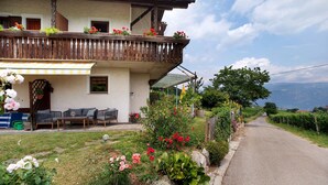 A house with a balcony, outdoor seating, and a garden.