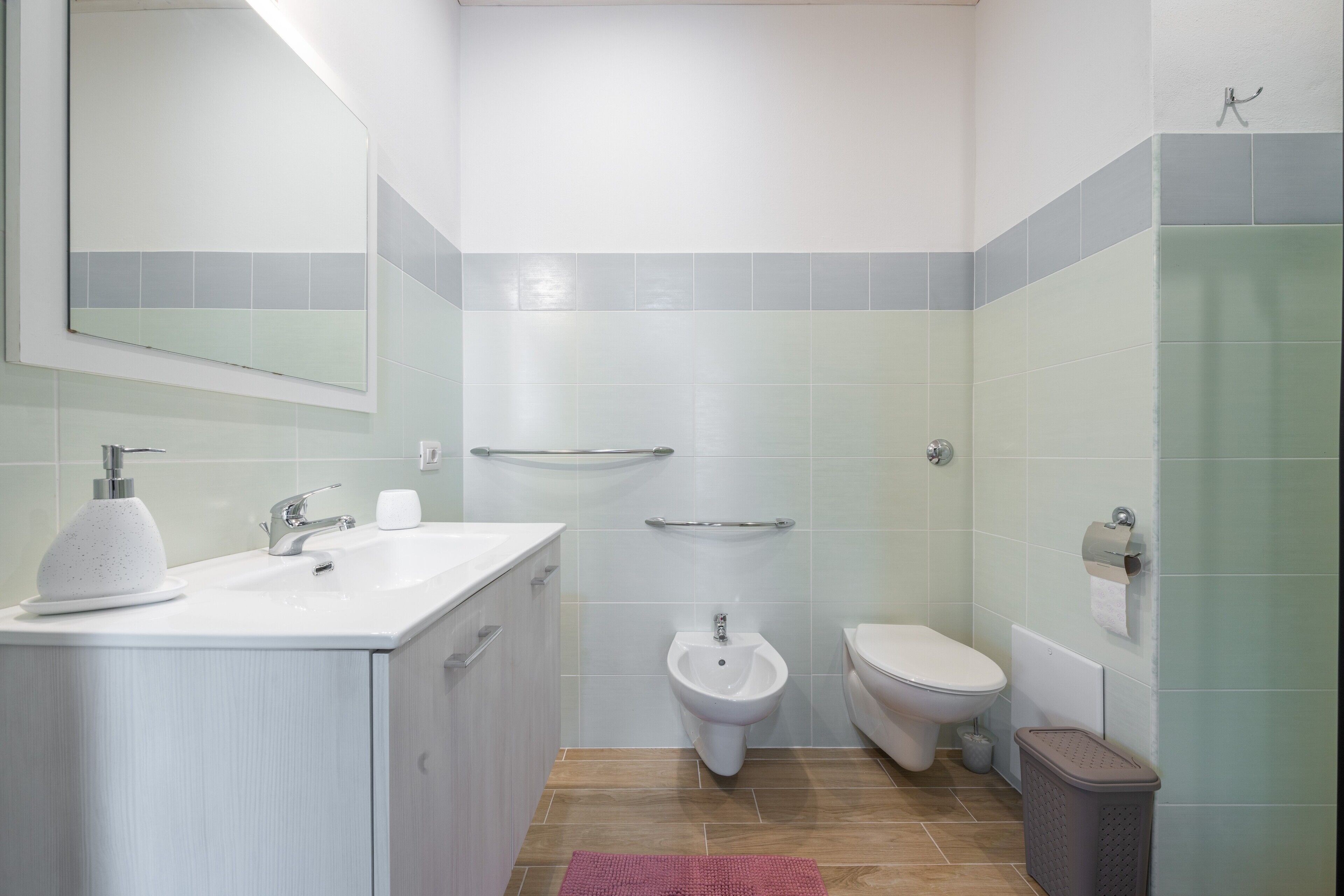 Un baño con lavamanos, bidé, inodoro y un cubo de basura.