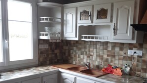 Una cocina con armarios blancos, un salpicadero de azulejos, una ventana y una encimera con un lavamanos.