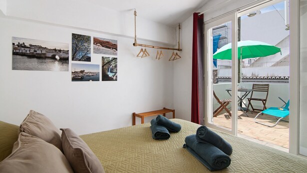 A room with a bed, a bench, a table, and a view of the outside. - Holiday Home 'Casa Da Avó Edite' with Private Terrace, Wi-Fi & Air Conditioning (Tavira)