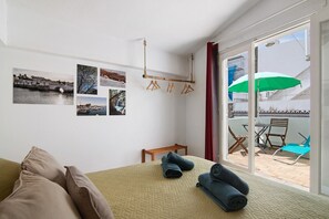 Una habitación con cama, un banco, una mesa y vistas al exterior.