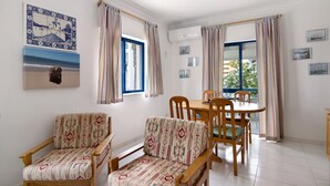 Ein Zimmer mit zwei Holzstühlen, einem Esstisch und einem Deckenventilator.