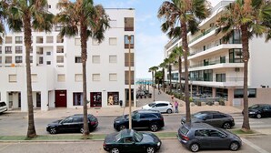 Ein mehrstöckiges Hotel mit Balkonen, parkenden Autos und Palmen.