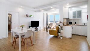 En moderne lejlighed med spiseområde, opholdsstue, køkken og havudsigt.
