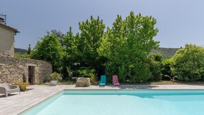 A swimming pool with lounge chairs, a stone wall, and lush greenery. - Holiday Gîte 'T1 Ardeche Vesseaux' with Mountain View, Shared Garden & Wi-Fi (Vesseaux)
