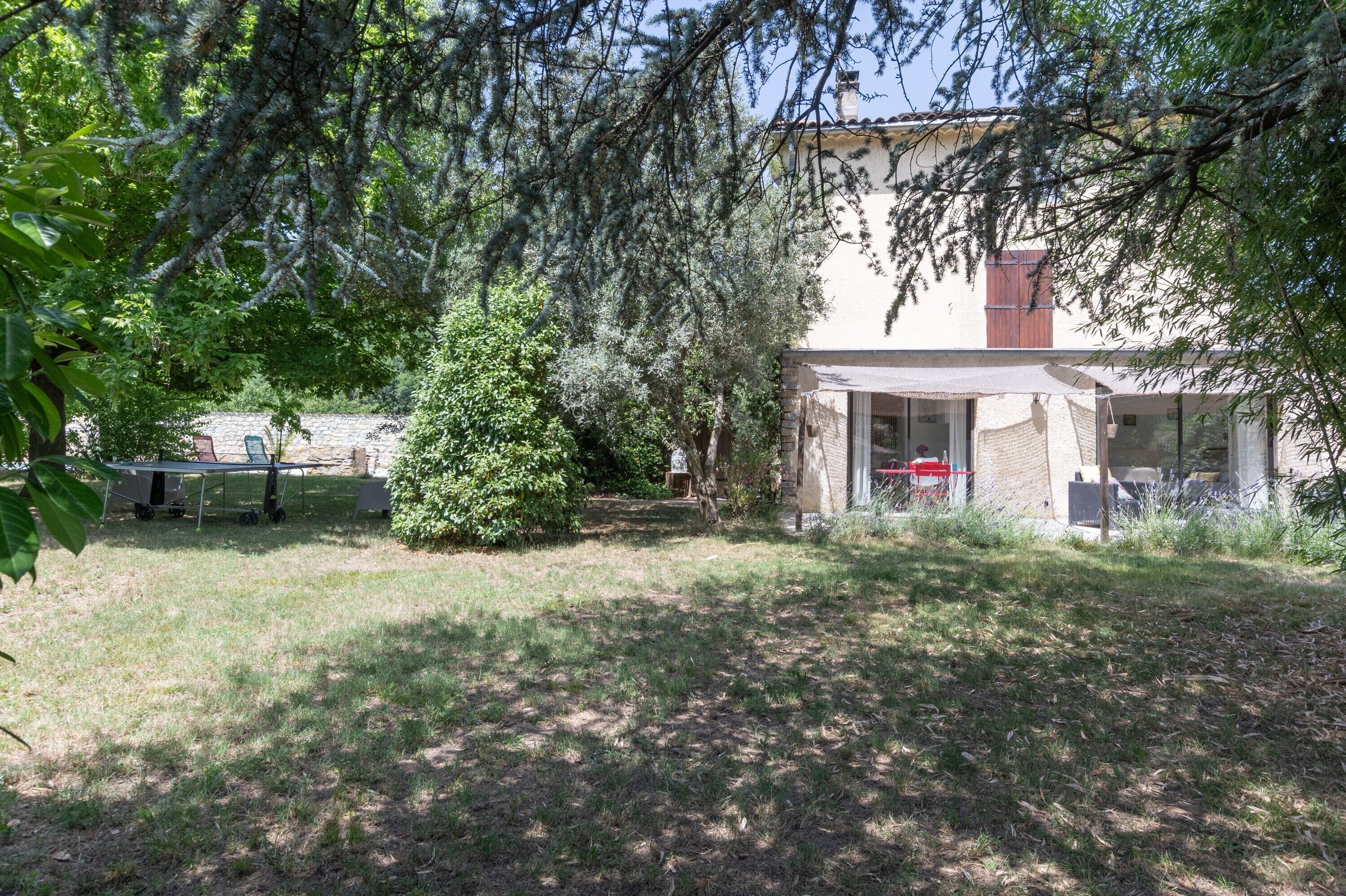 A house with a covered patio, a lawn, and a tree.