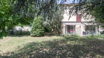 A house with a covered patio, a lawn, and a tree.