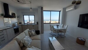 A modern apartment with a kitchen, dining area, and a large window offering a city view.