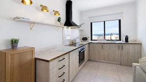 A modern kitchen with wooden cabinets, a built-in oven, and a window with a city view.