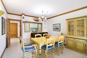 Un coin repas comprenant une table et des chaises en bois, un lustre et un buffet aux portes vitrées.