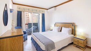 Een hotelkamer met een bed, nachtkastje, bureau, stoel en uitzicht.