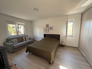 Une chambre à coucher avec un lit, un canapé, une petite table et deux fenêtres.