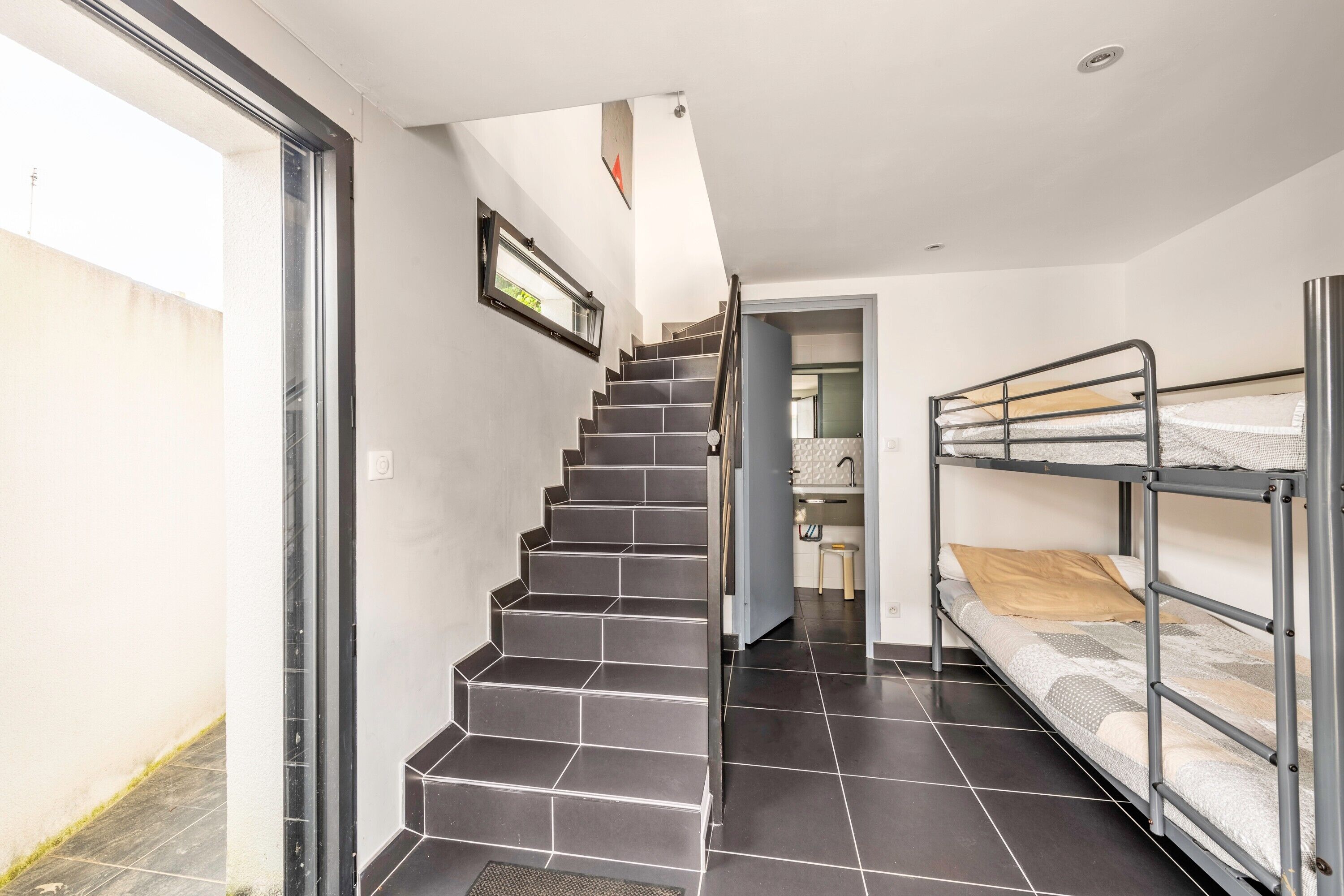 Een trap die leidt naar een slaapkamer met stapelbedden en uitzicht op de lucht.