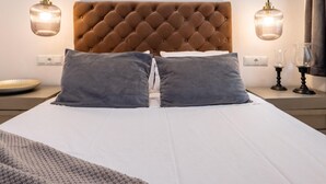 En pænt redt seng med en knoppetopstykke, to sengetårnslamper og et natbord med en glasvase.
