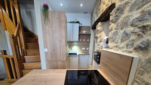 Une cuisine moderne avec des meubles en bois, une cuisinière encastrée et un mur d’accent en pierre.