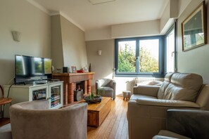 A living room with a television, sofa, armchair, and a fireplace.