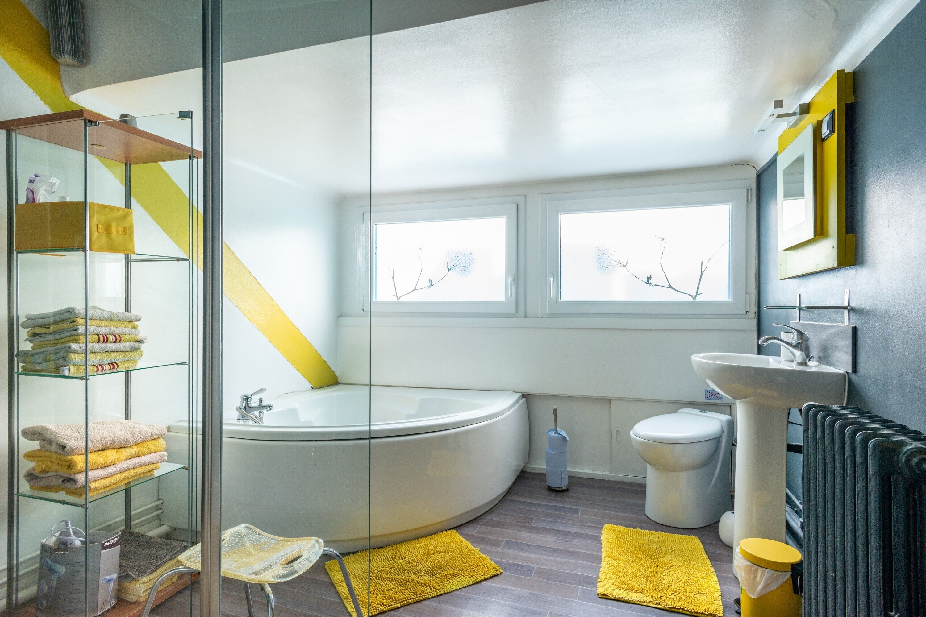 Een moderne badkamer met een douchecabine van glas, een vrijstaand bad, een toilet en een wastafel.