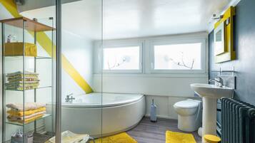 Een moderne badkamer met een douchecabine van glas, een vrijstaand bad, een toilet en een wastafel.
