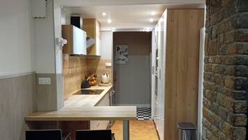 Een moderne keuken met een houten aanrecht, twee barkrukken en een stenen muur.