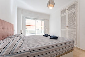 Ein Schlafzimmer mit Bett, Fenster, Tür und einer Lampe.