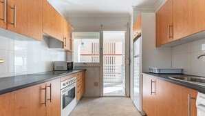 Eine schmale Küche mit Holzausstattung, einer Mikrowelle und einem Kühlschrank.