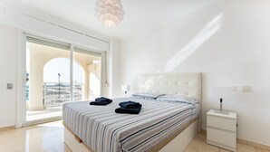Ein Schlafzimmer mit einem großen Bett, einem Nachttisch, einer Fensterstube und Blick durch eine Glastür.