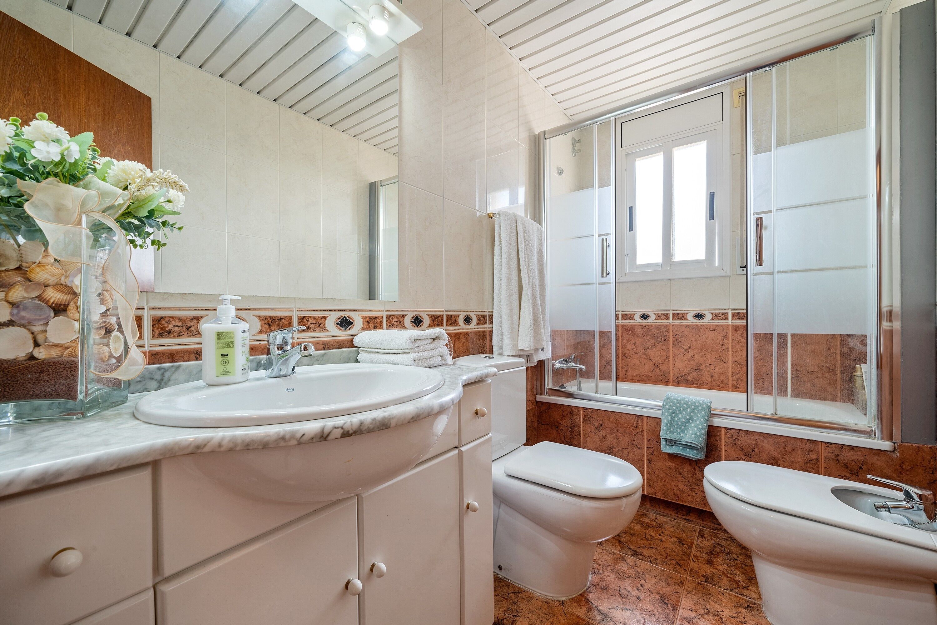 A bathroom with a marble sink, two toilets, a shower, and a large mirror.