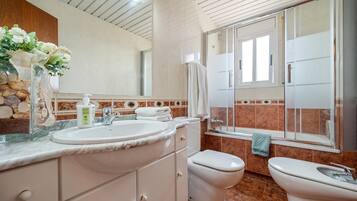A bathroom with a marble sink, two toilets, a shower, and a large mirror.